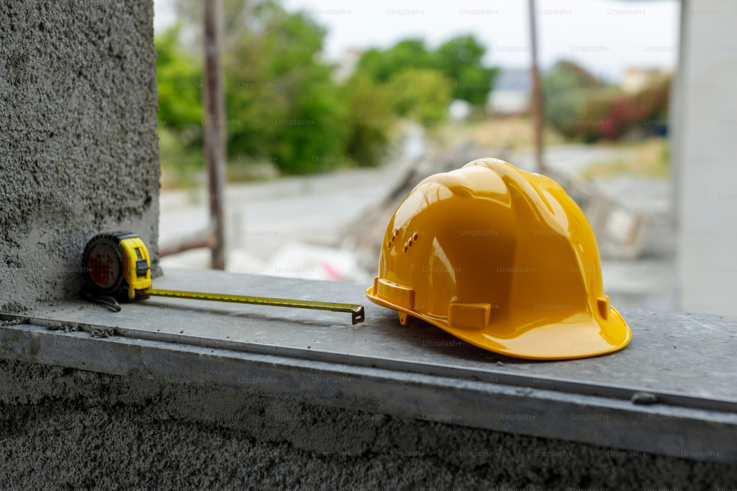 Yellow construction helmet and a metering scale on concrete ledge