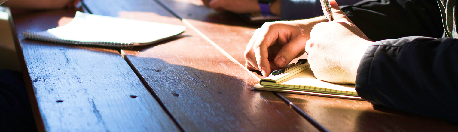 Team members in a sunlit meeting room taking notes during a group discussion