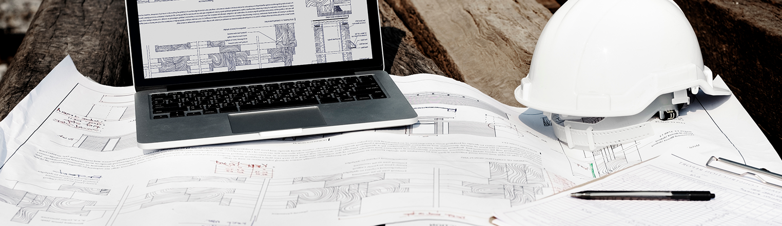 A blueprint with a laptop, helmet and a checklist on top of it